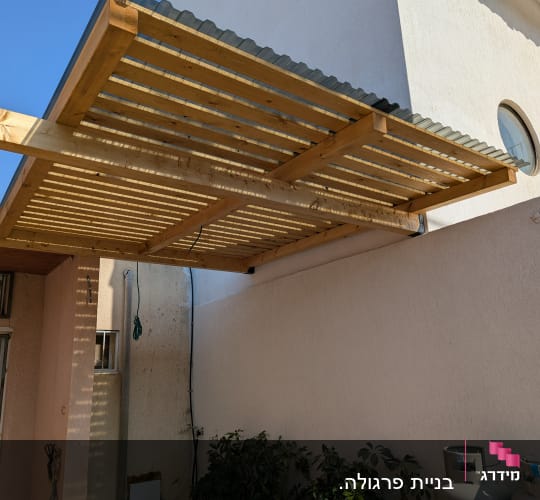 פרגולה מעץ צמודה לקיר חיצוני של בית